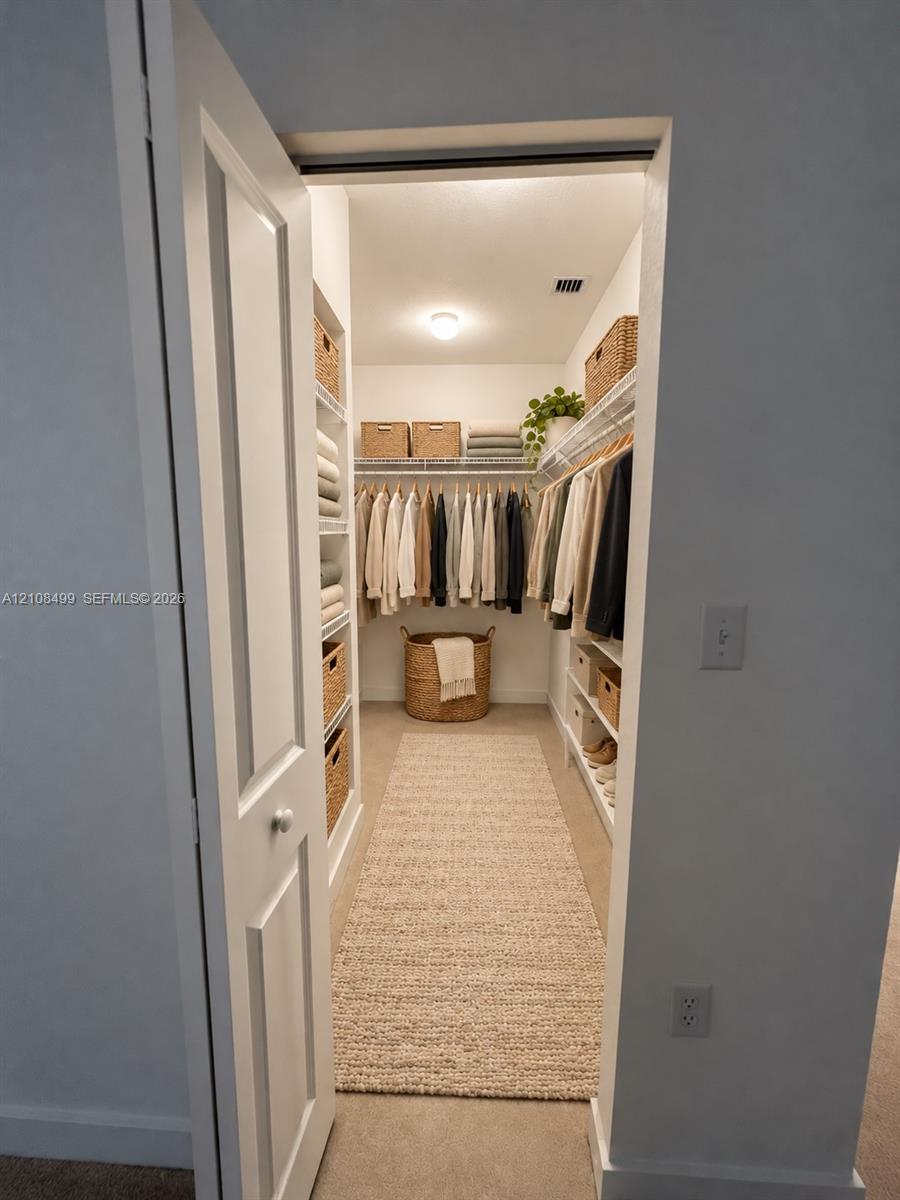 Walk-in storage space featuring built-in shelving, wire racking, and a flush-mount ceiling light