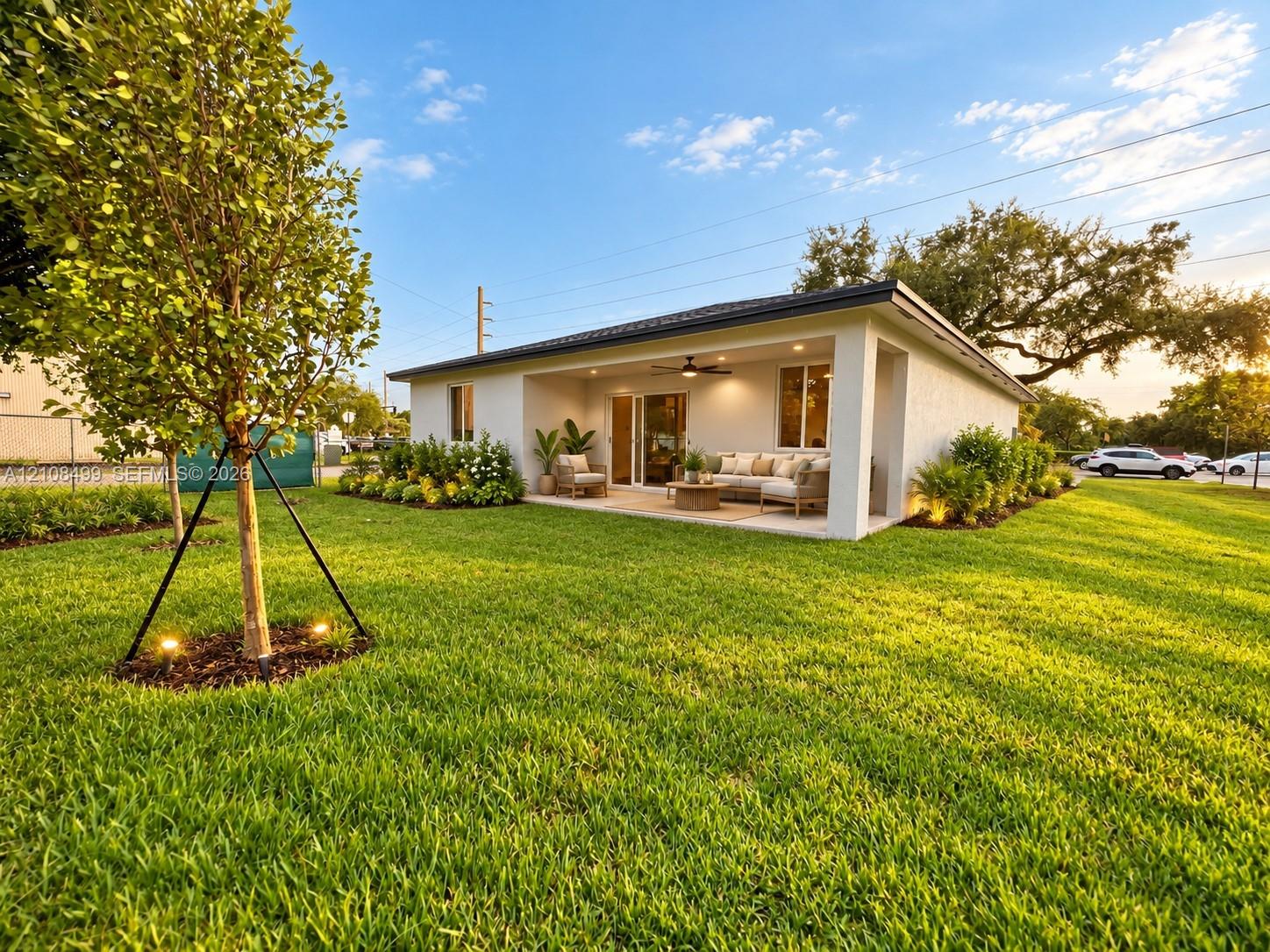 Stucco exterior featuring a covered patio, recessed ceiling lighting, a mounted ceiling fan, and landscaped grounds