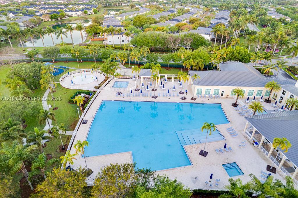 Large swimming pool with tiered entry, secondary splash pad, integrated spa, expansive stone-paver deck, and covered pavilion