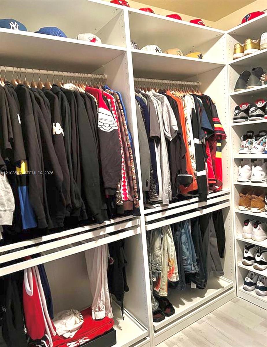 Custom floor-to-ceiling white shelving system with integrated hanging rods and dedicated shoe display cubbies