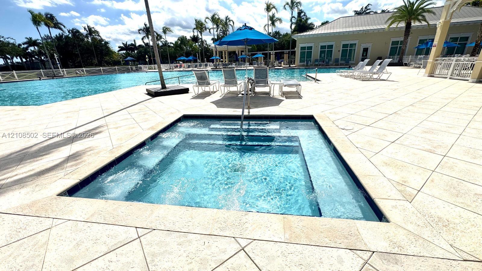In-ground spa with stone-tile surround, expansive swimming pool, and stone-paved patio deck