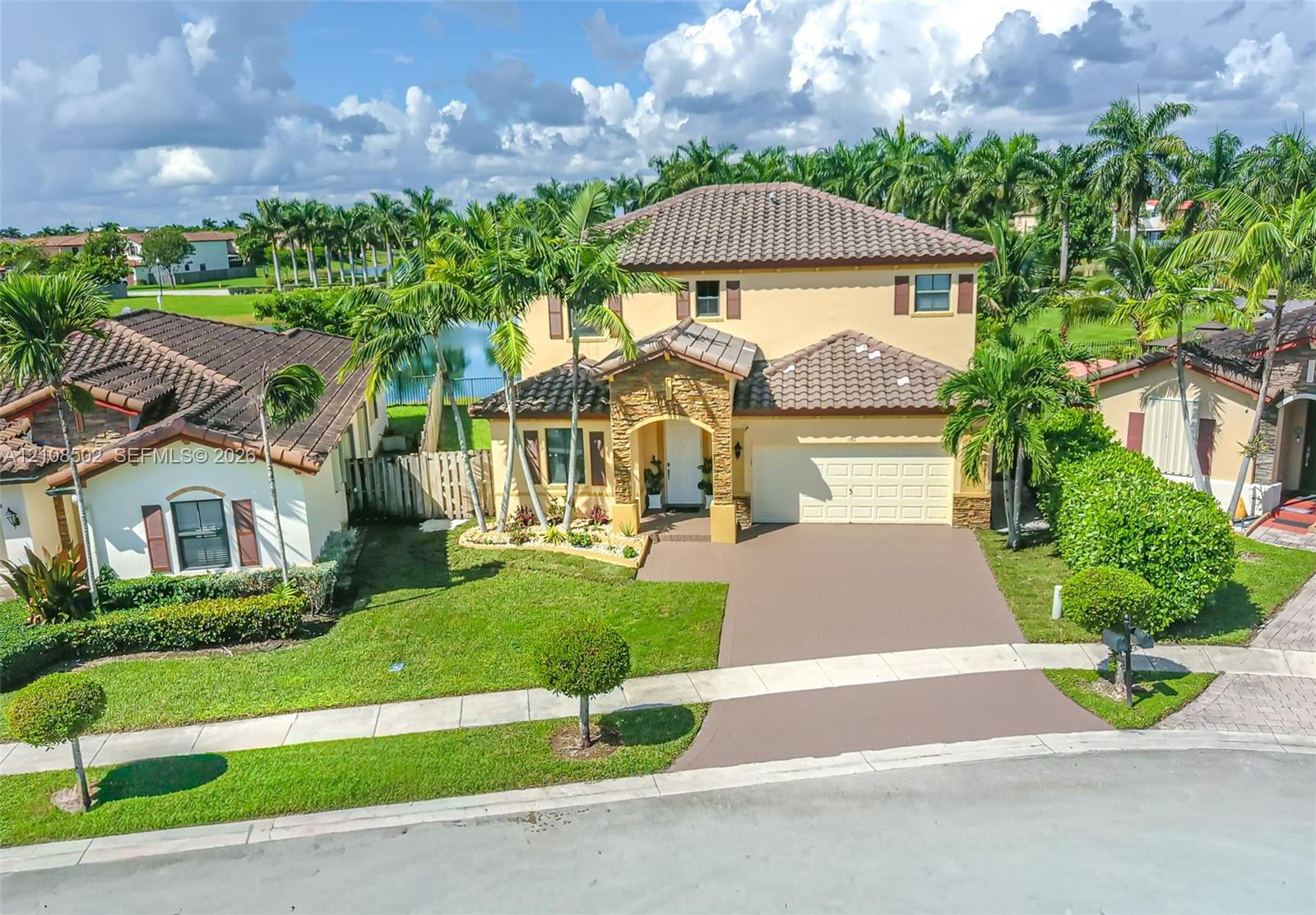 Two-story exterior featuring a tile roof, stone masonry facade detail, paved driveway, and established landscaping