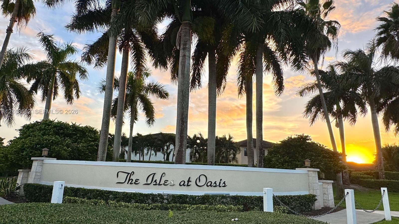 Stone masonry signage featuring a cast-stone finish, complemented by mature palm trees and landscaped greenery