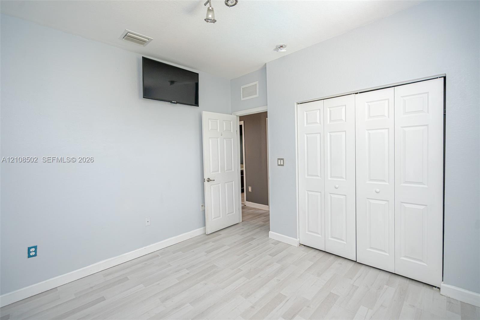 Light-toned wood-finish flooring, six-panel interior doors, and bi-fold closet doors with recessed panels