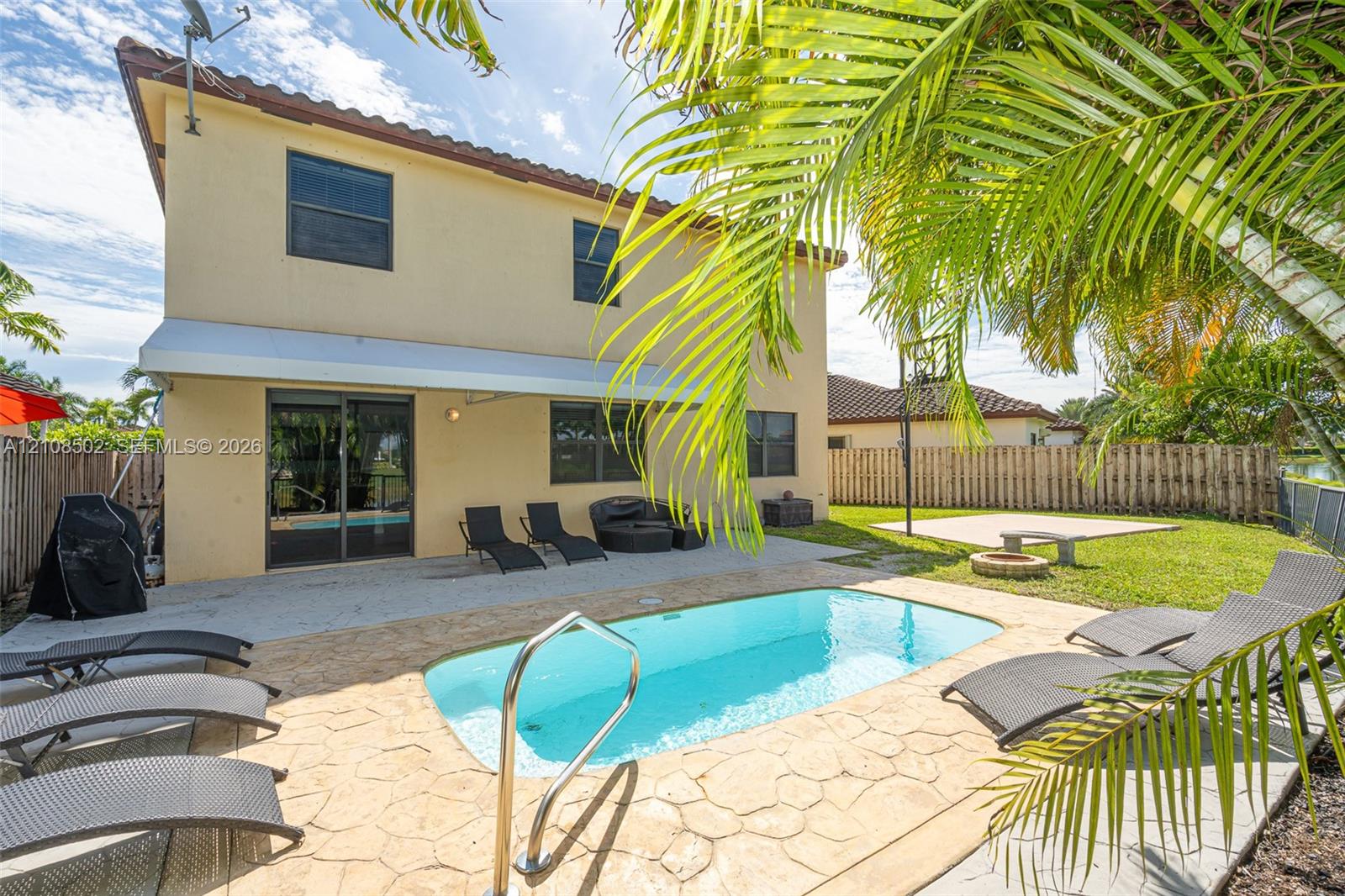 Rear exterior featuring a stucco facade, concrete tile roofing, a paved patio, an in-ground swimming pool, and a fenced backyard