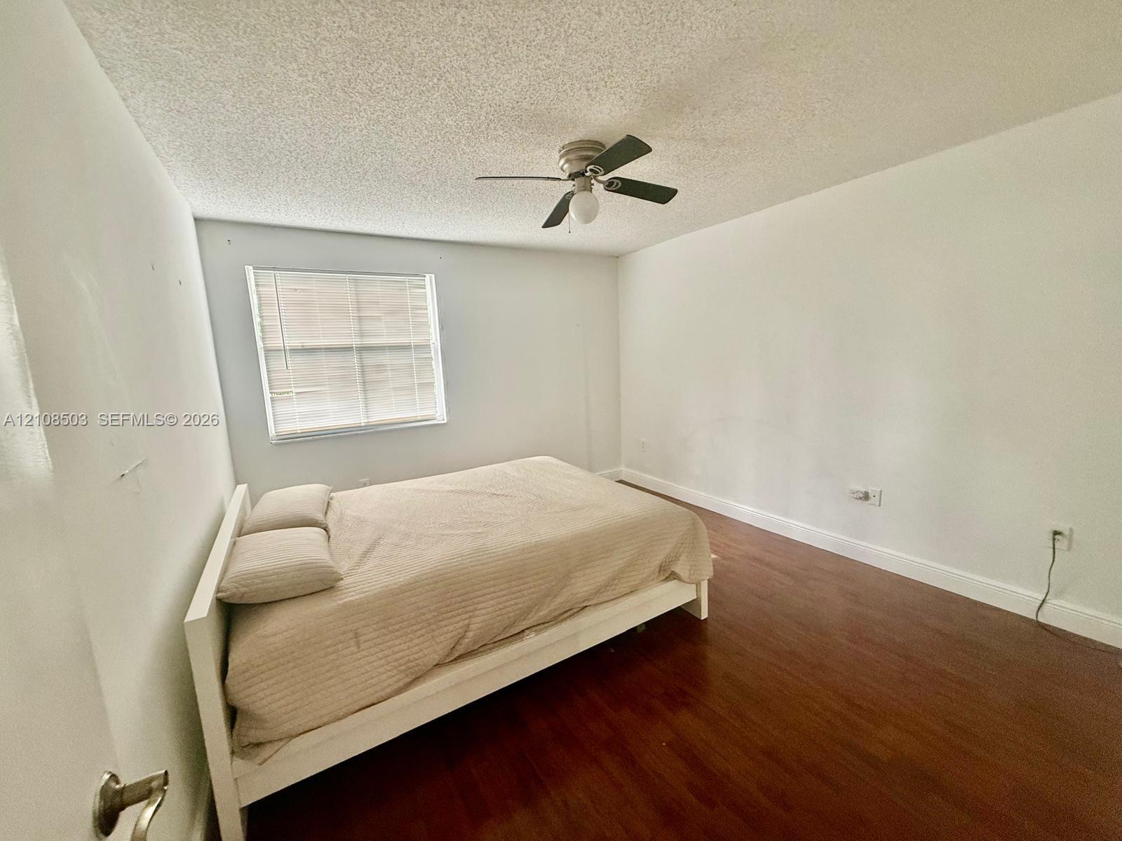 Room featuring wood-finish flooring, a ceiling fan with integrated lighting, and a window with horizontal blinds Room featuring wood-finish flooring, a ceiling fan with integrated lighting, and a window with horizontal blinds