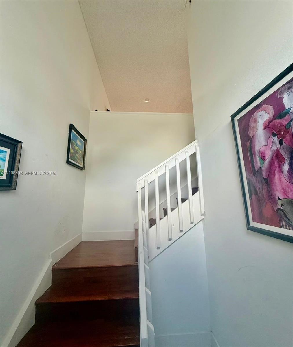 Staircase featuring wood-finish treads and a white wooden balustrade beneath a vaulted ceiling with recessed lighting Staircase featuring wood-finish treads and a white wooden balustrade beneath a vaulted ceiling with recessed lighting