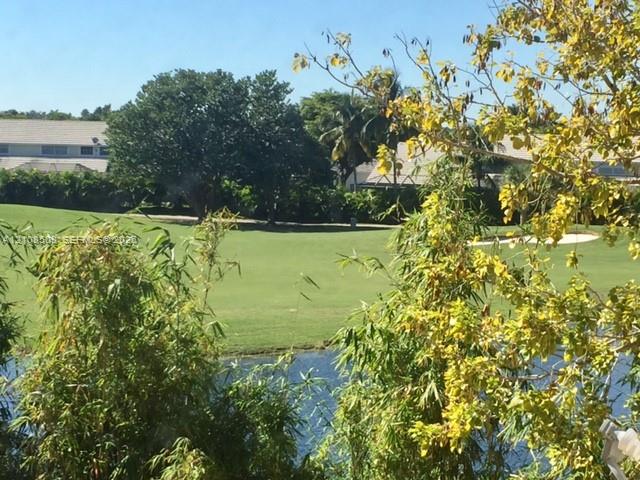 Expansive grounds featuring a water feature, manicured turf, mature trees, and a sand bunker