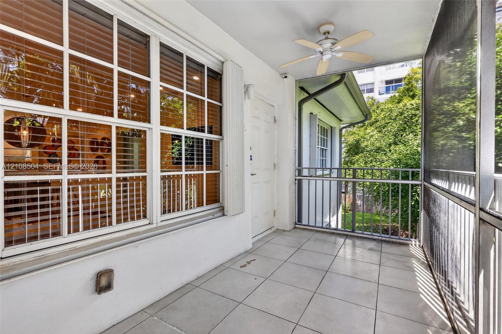 Screened-in balcony featuring tile flooring, a ceiling fan, and metal railings