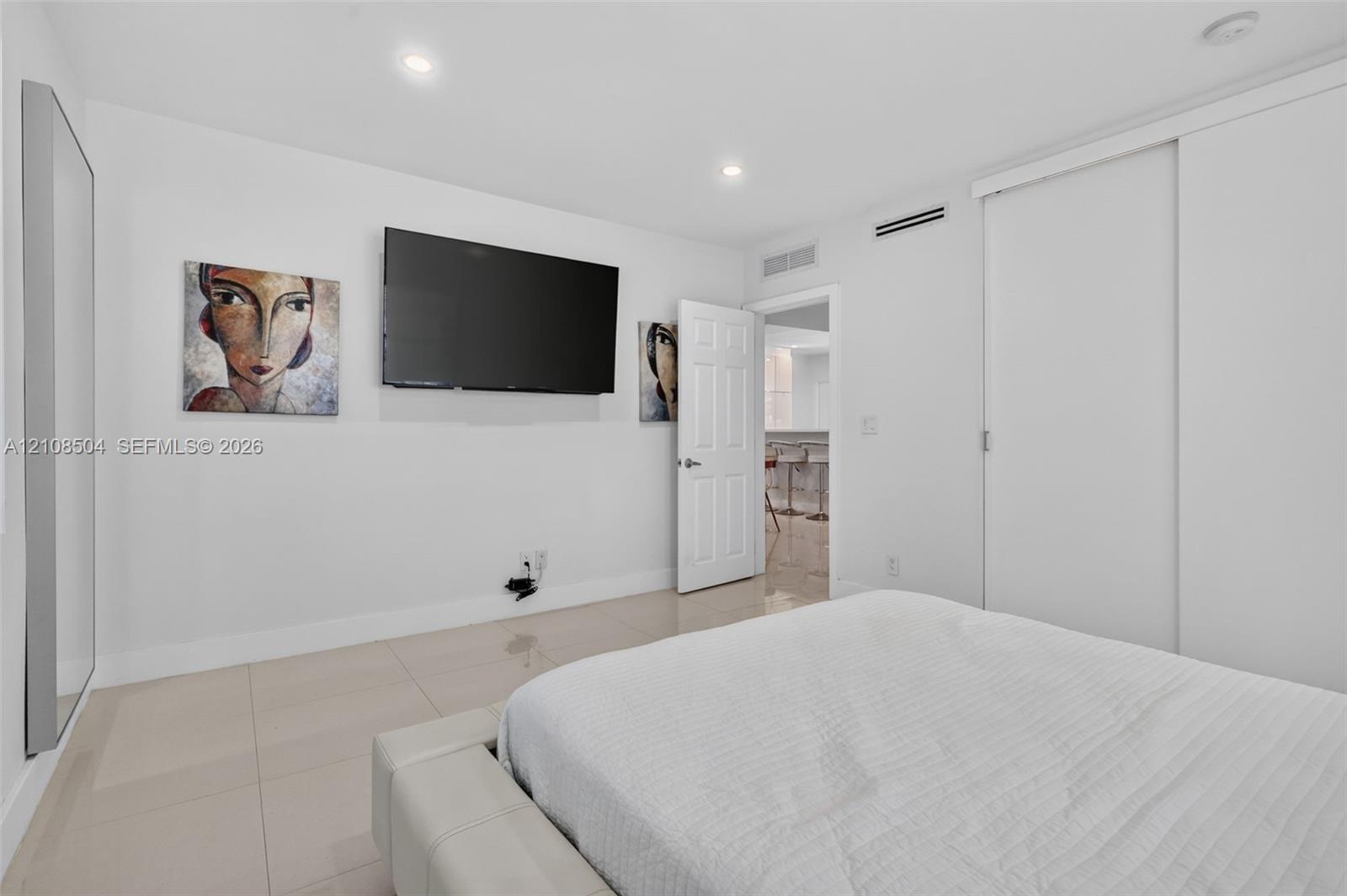 Neutral-toned tile flooring, recessed ceiling lighting, and sliding closet doors with white finish