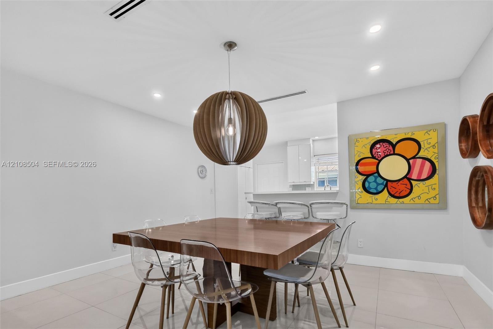 Dining area featuring large-format tile flooring, recessed ceiling lighting, and a spherical wooden pendant fixture