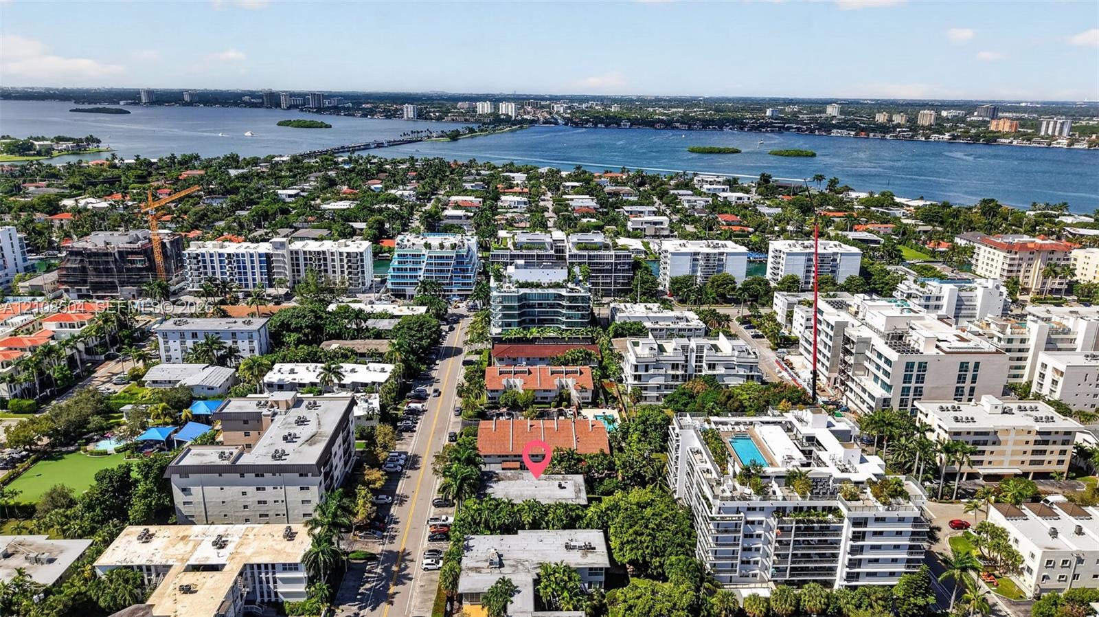 Aerial perspective featuring a property location within a dense coastal residential area, characterized by proximity to the waterfront and surrounding mature vegetation