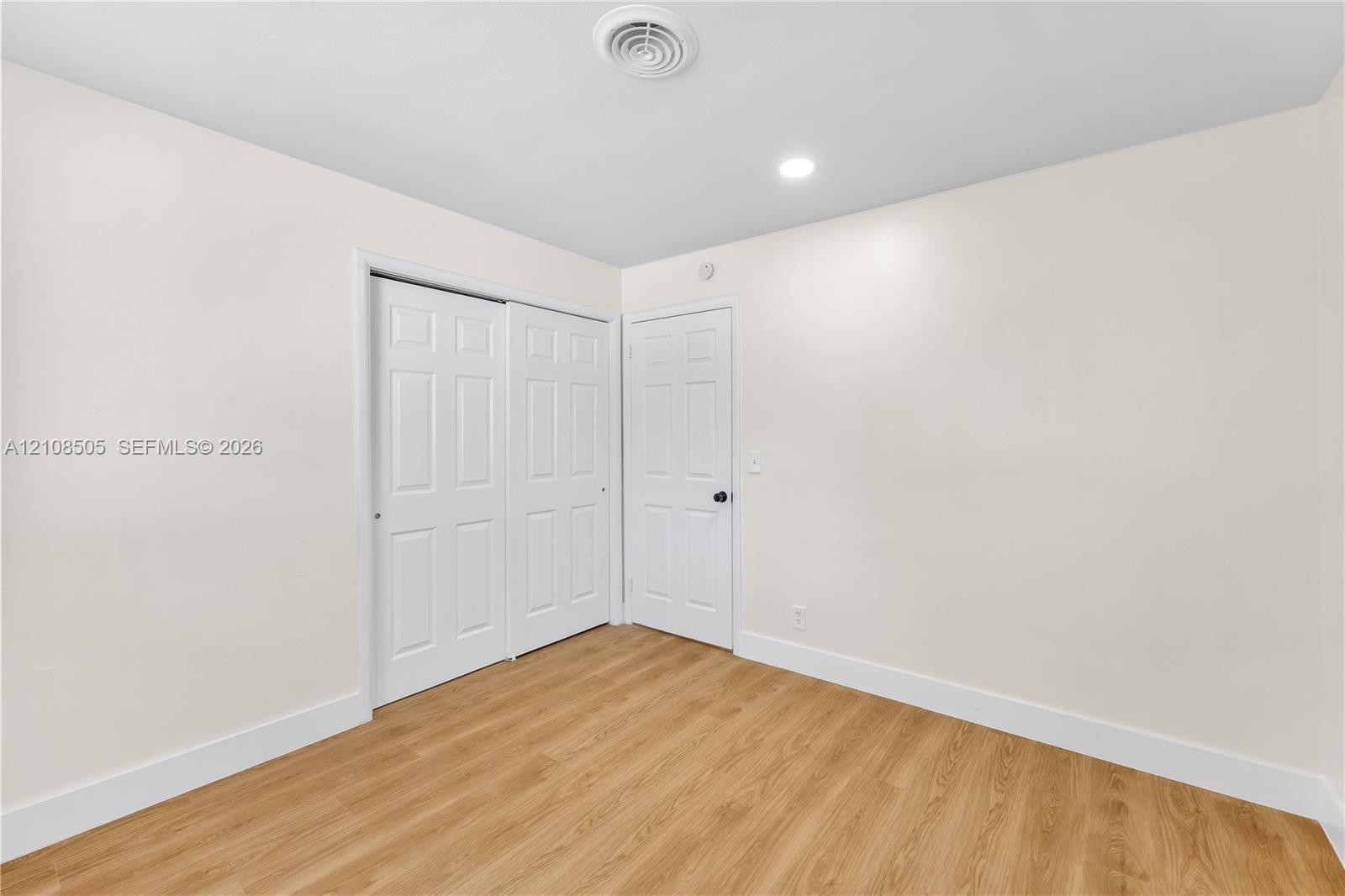 Neutral interior space featuring wood-finish flooring, recessed lighting, and a double-panel sliding closet
