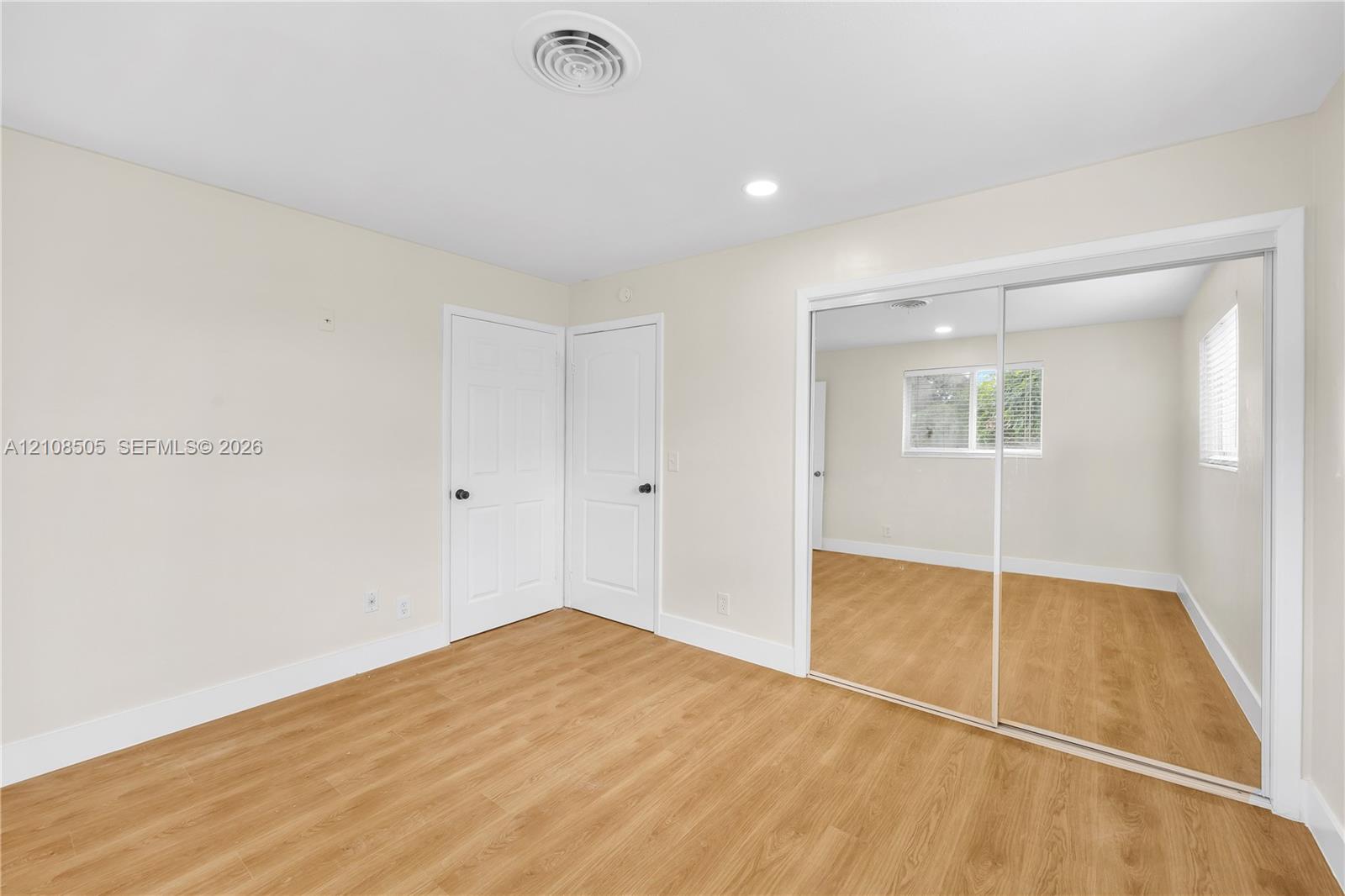 Neutral interior featuring wood-finish flooring, recessed lighting, and a closet with sliding mirrored doors