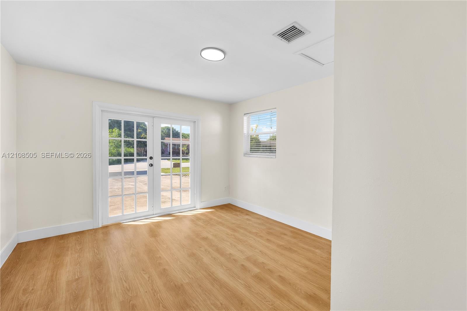 Neutral-toned interior featuring wood-finish flooring, glass-paned double doors, and a recessed ceiling light