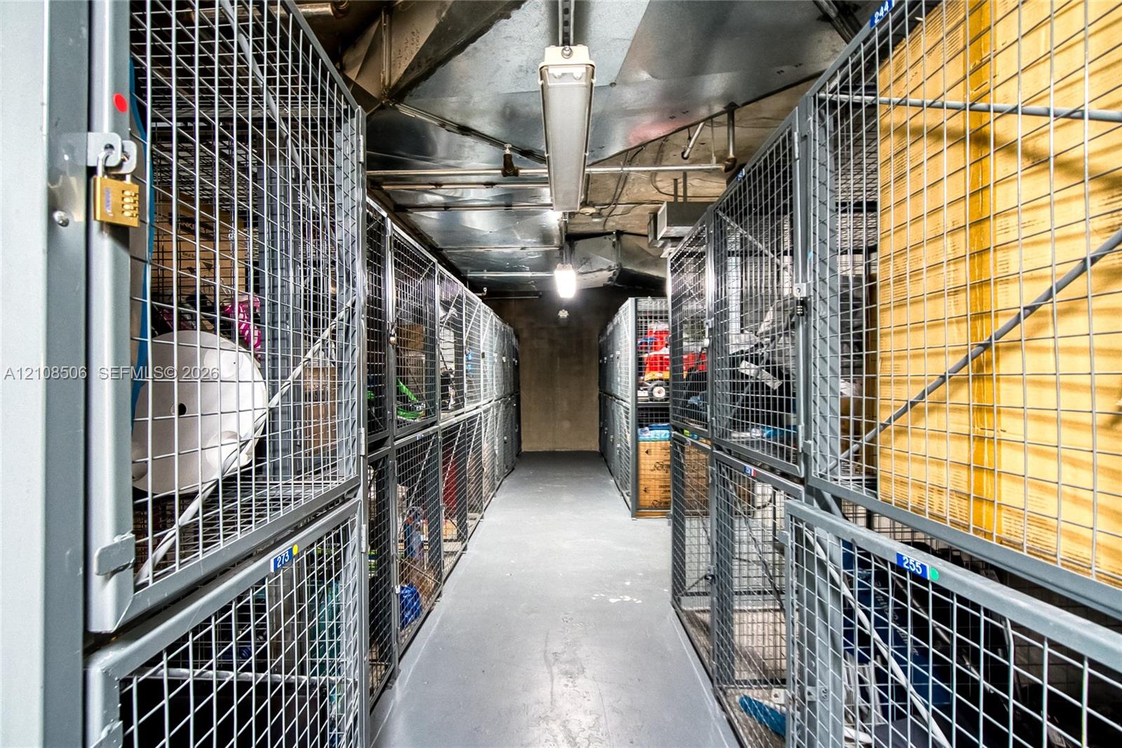 Storage area featuring stacked metal wire-mesh lockers, concrete flooring, and overhead industrial lighting