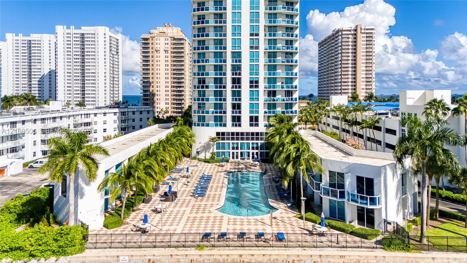 High-rise residential exterior featuring a paved pool deck, custom-shaped swimming pool, integrated landscaping, and private balconies