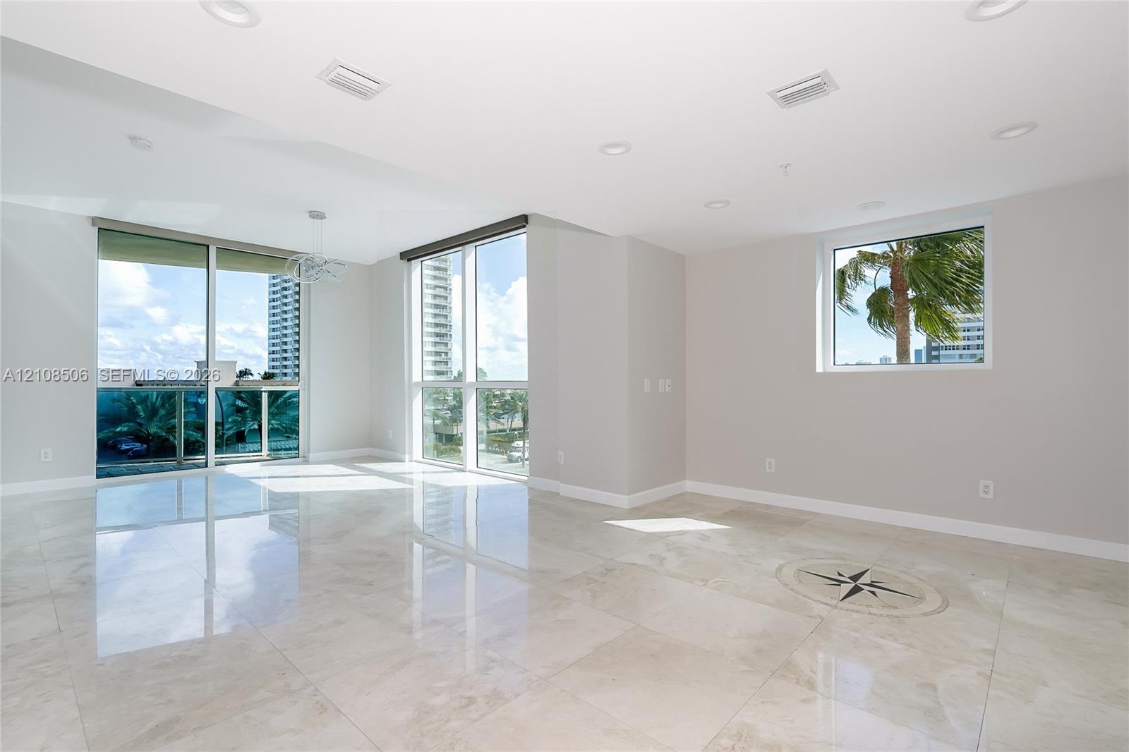 Large-format tile flooring, recessed ceiling lighting, floor-to-ceiling glass sliding doors, custom stone floor inlay, and expansive windows