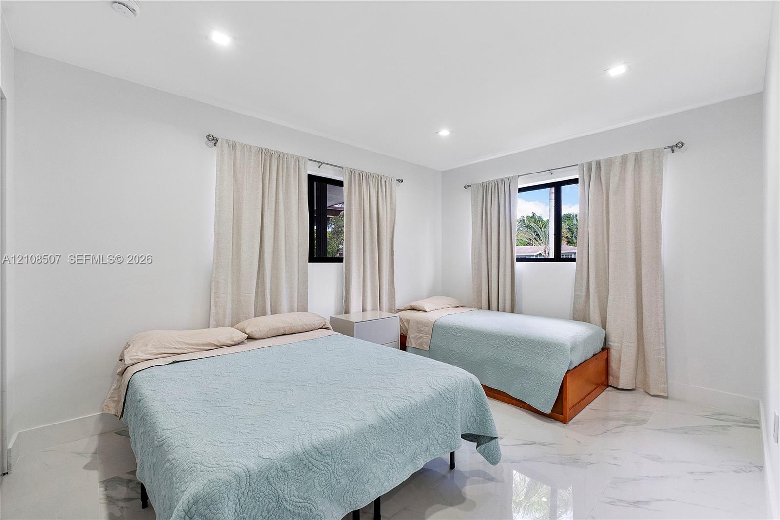 Neutral wall tones, polished stone-finish flooring, recessed ceiling lighting, and black-framed windows