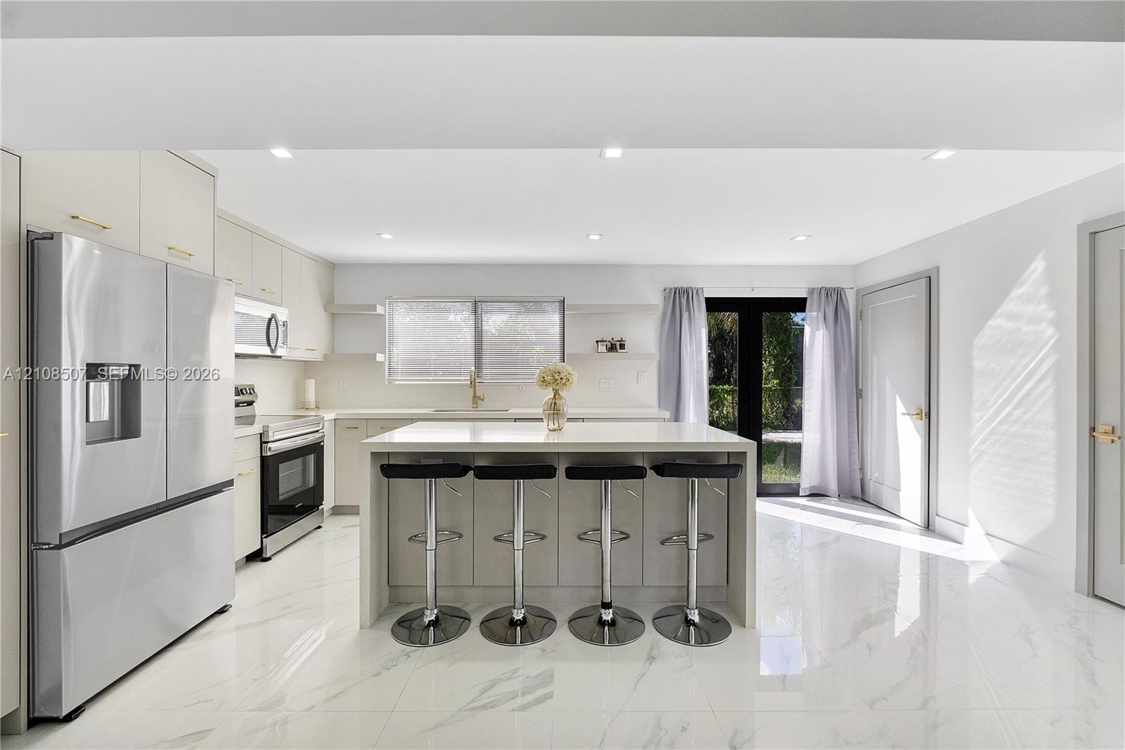 Kitchen featuring white cabinetry, a center island with a stone-finish countertop, stainless steel appliances, recessed lighting, and large-format tile flooring