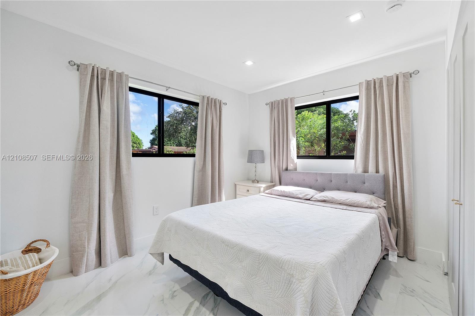 Neutral-toned interior featuring recessed lighting, polished stone-finish flooring, and black-framed windows