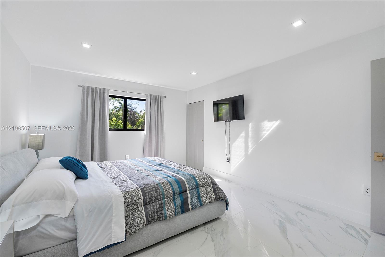 Bright room featuring polished white stone-finish flooring, recessed LED lighting, and a window with black frames