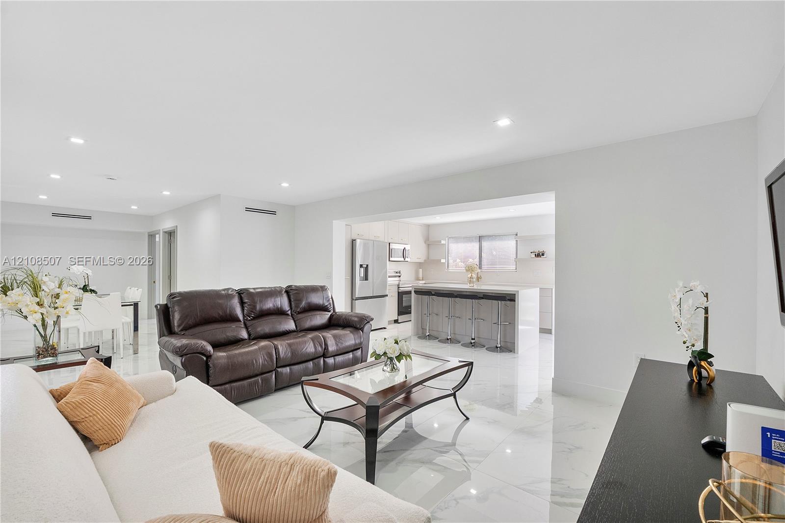 Open floor plan featuring recessed lighting, polished stone-finish tile flooring, and a kitchen island with stone-finish countertop