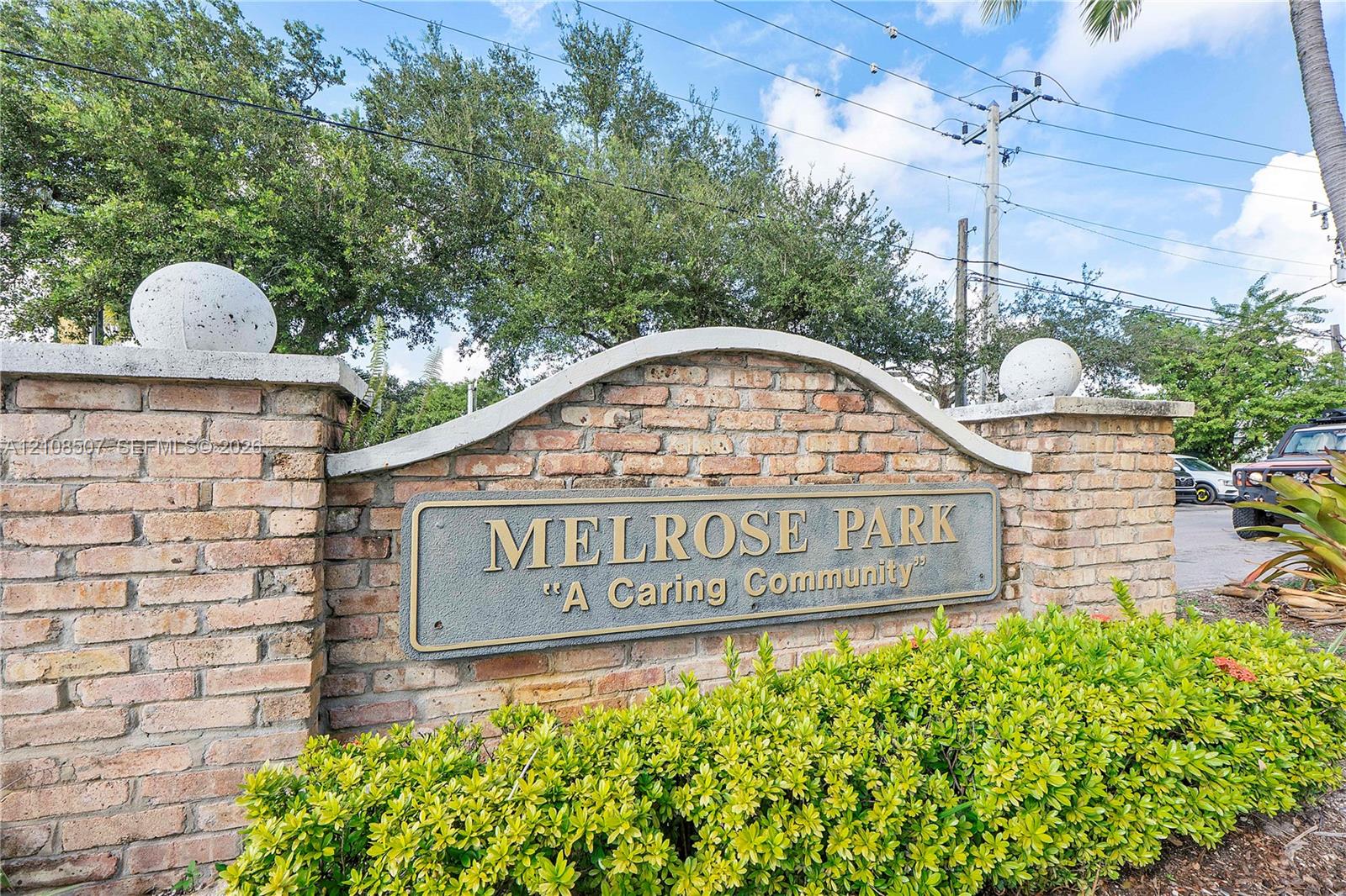 Brick entrance monument featuring a custom arch cap, spherical finials, and mature landscaping
