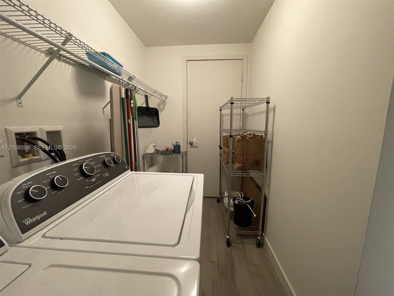 Laundry area featuring wood-finish flooring and integrated wall-mounted wire shelving