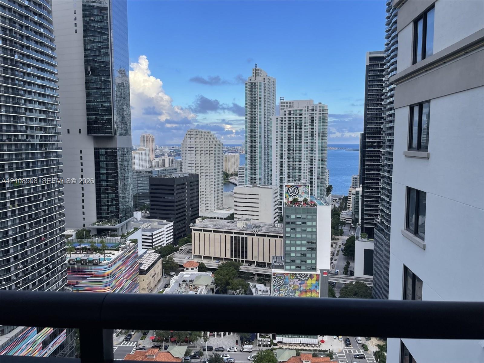 High-rise balcony featuring a metal railing with a skyline and coastal water horizon