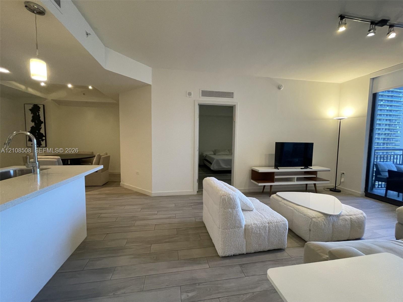 Open-concept interior featuring wood-finish tile flooring, a peninsula with stone countertop, recessed lighting, and floor-to-ceiling glass sliding doors