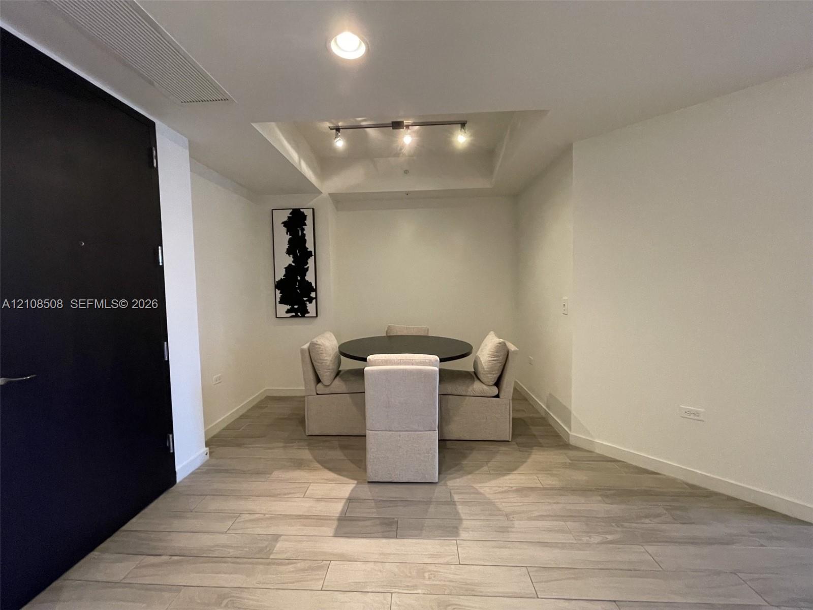 Interior space featuring wood-finish tile flooring, recessed ceiling lighting, a tray ceiling detail, and a matte black door