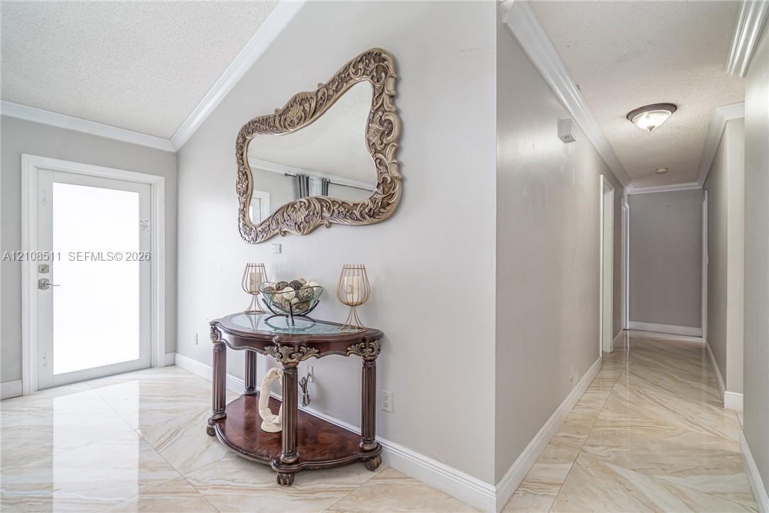Entryway featuring large-format tile flooring, vaulted ceilings, crown molding, and a neutral color palette Entryway featuring large-format tile flooring, vaulted ceilings, crown molding, and a neutral color palette