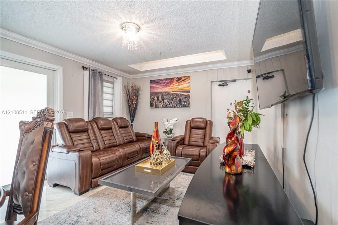 Living area featuring a recessed ceiling tray, crystal-style chandelier, and glass sliding door Living area featuring a recessed ceiling tray, crystal-style chandelier, and glass sliding door
