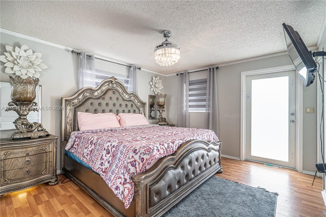 Wood-finish flooring, crystal-accented flush mount ceiling light, and a glass-paneled exterior door