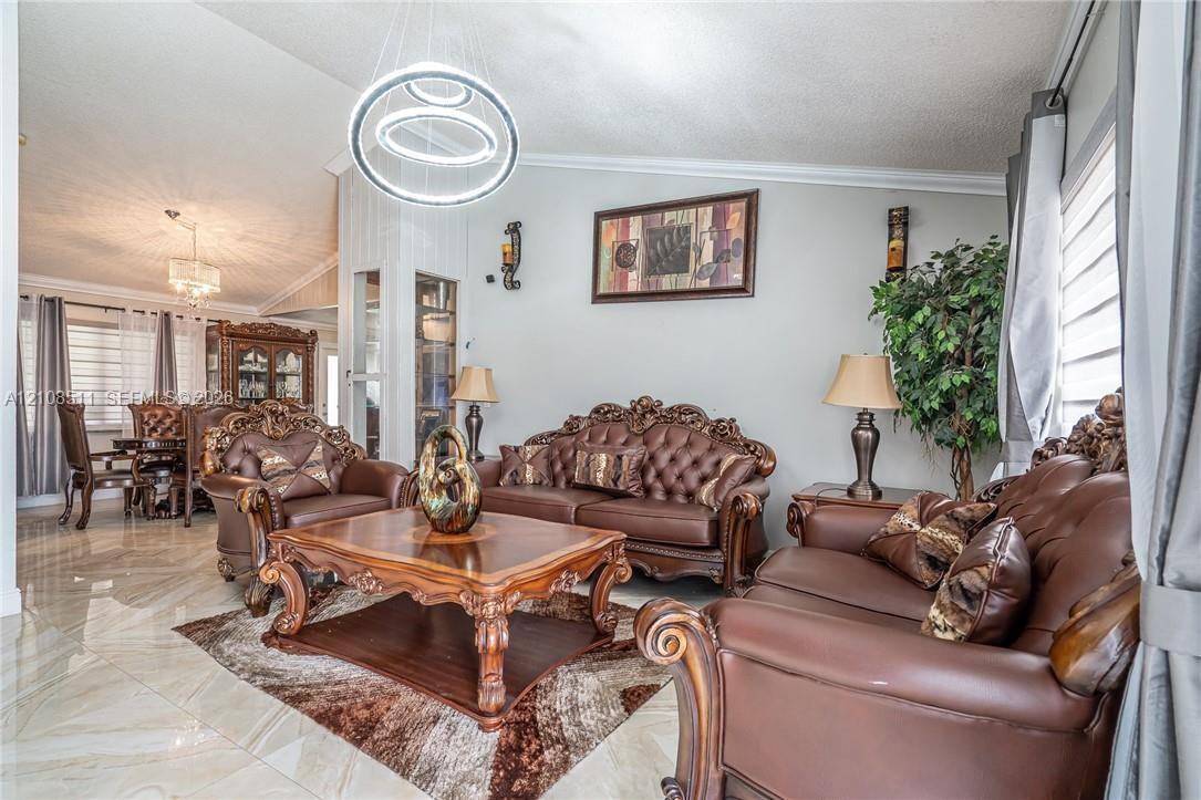 Vaulted ceilings, large-format tile flooring, modern dual-ring LED chandelier, and built-in glass-paneled display cabinetry