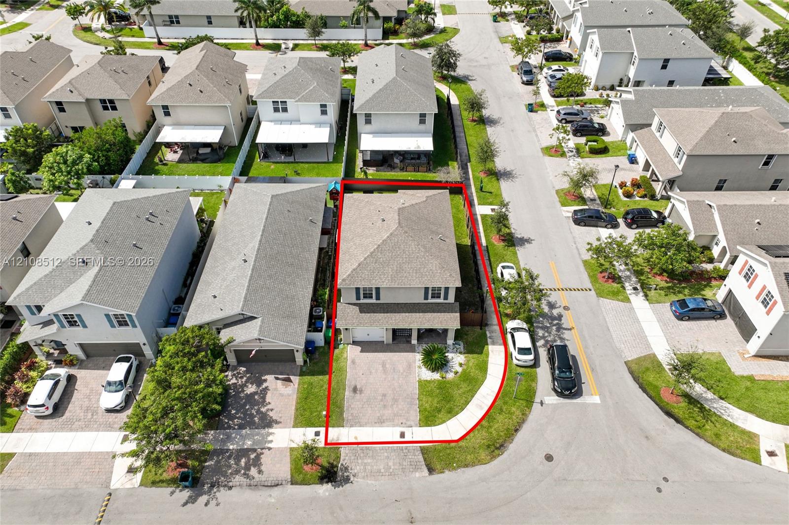 Two-story residence featuring a paved driveway, attached garage, shingled hip roof, and a corner lot configuration