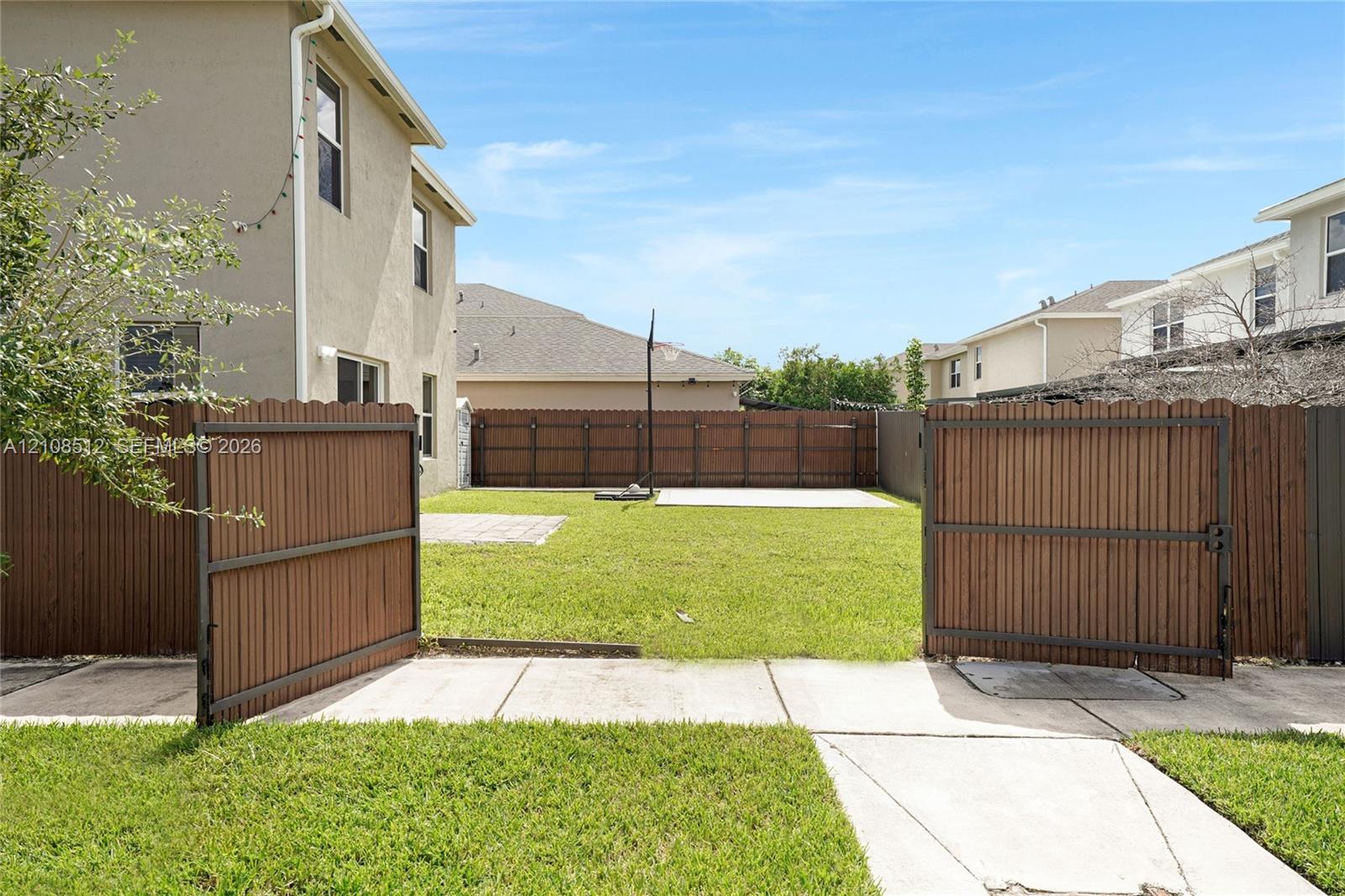 Fenced backyard featuring a manicured lawn, paved patio area, and wooden privacy fencing