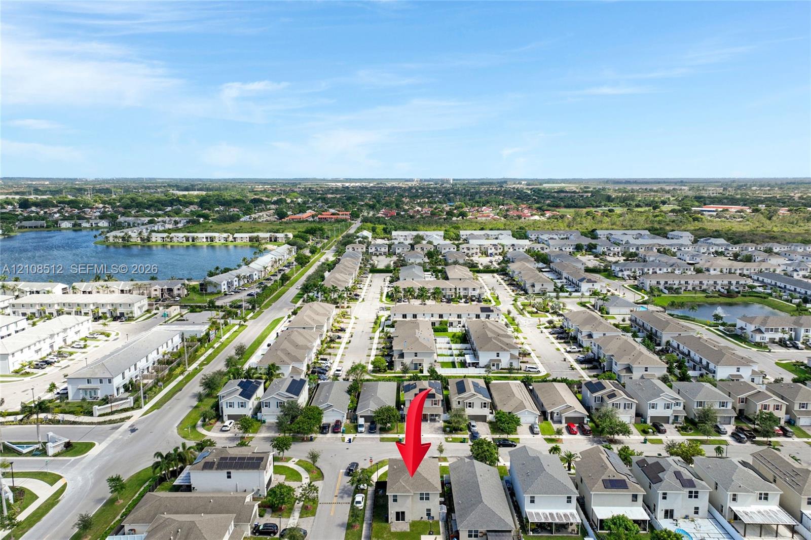 Aerial perspective of a multi-story residence featuring a neutral-toned exterior, concrete tile roof, solar panels, and a rear grassy yard