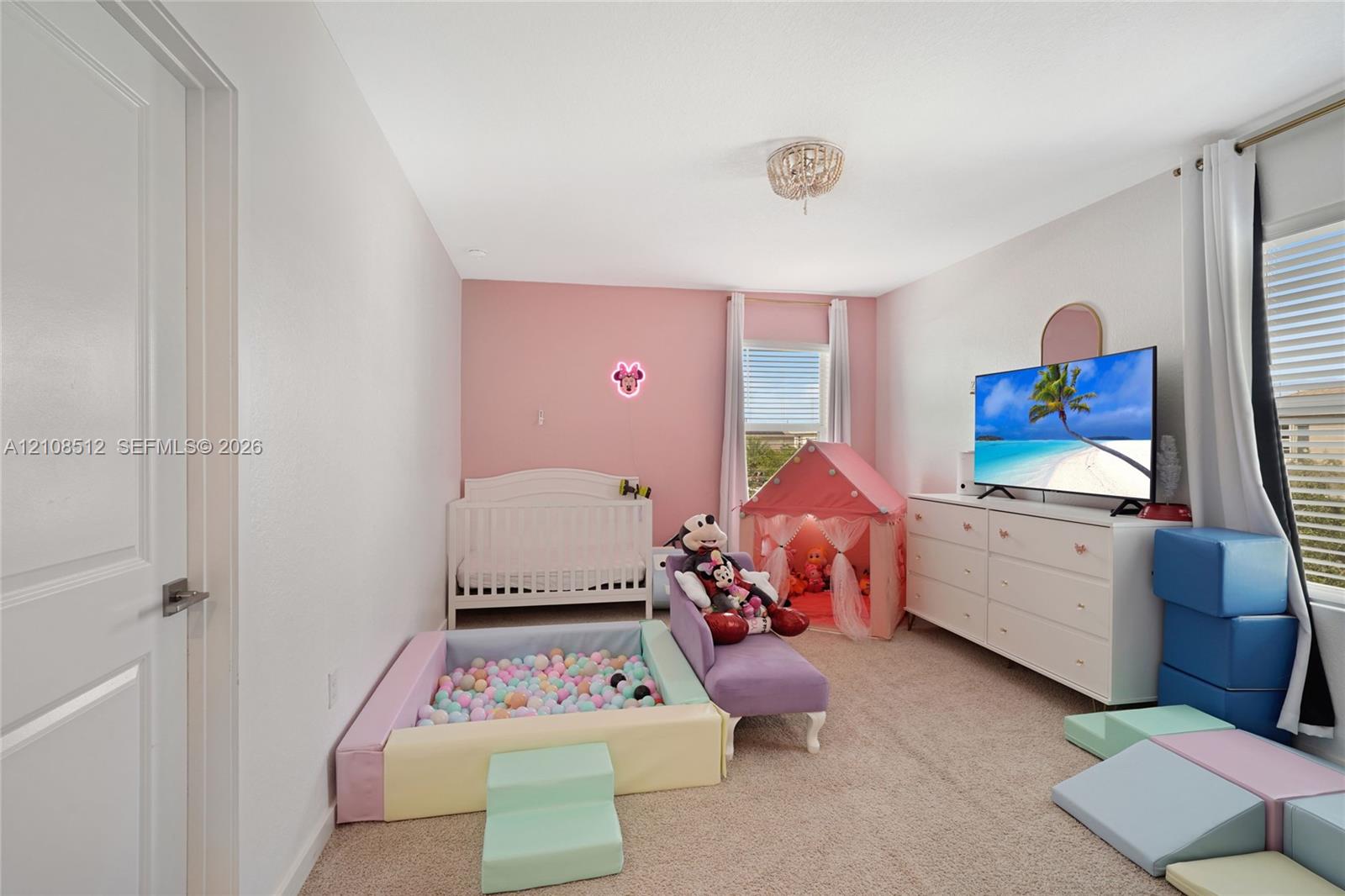 Neutral-toned carpeted room featuring an accent wall, two windows with horizontal blinds, and a circular ceiling-mounted light fixture Neutral-toned carpeted room featuring an accent wall, two windows with horizontal blinds, and a circular ceiling-mounted light fixture