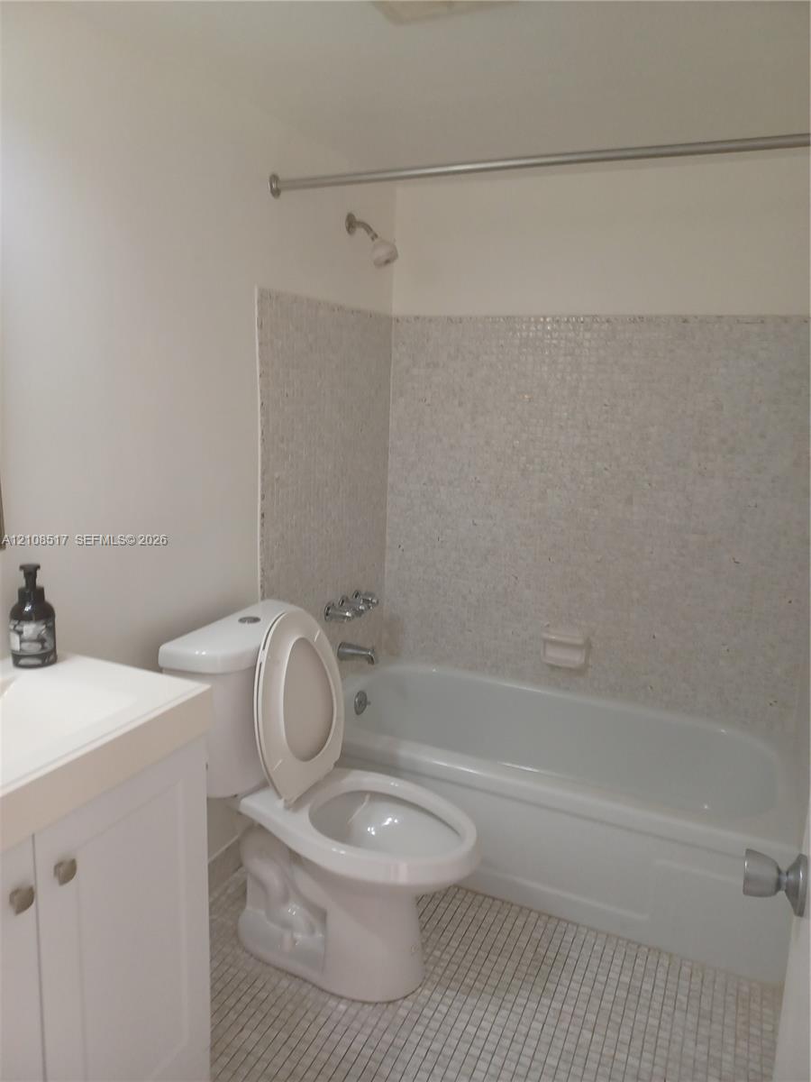 Bathroom featuring a porcelain tub with tile surround, a built-in vanity cabinet, and tiled flooring Bathroom featuring a porcelain tub with tile surround, a built-in vanity cabinet, and tiled flooring