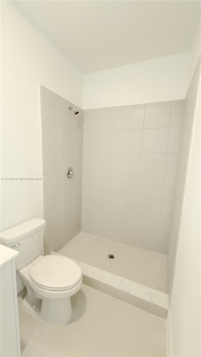 Walk-in shower with light-toned wall tile, porcelain shower basin, and chrome shower head