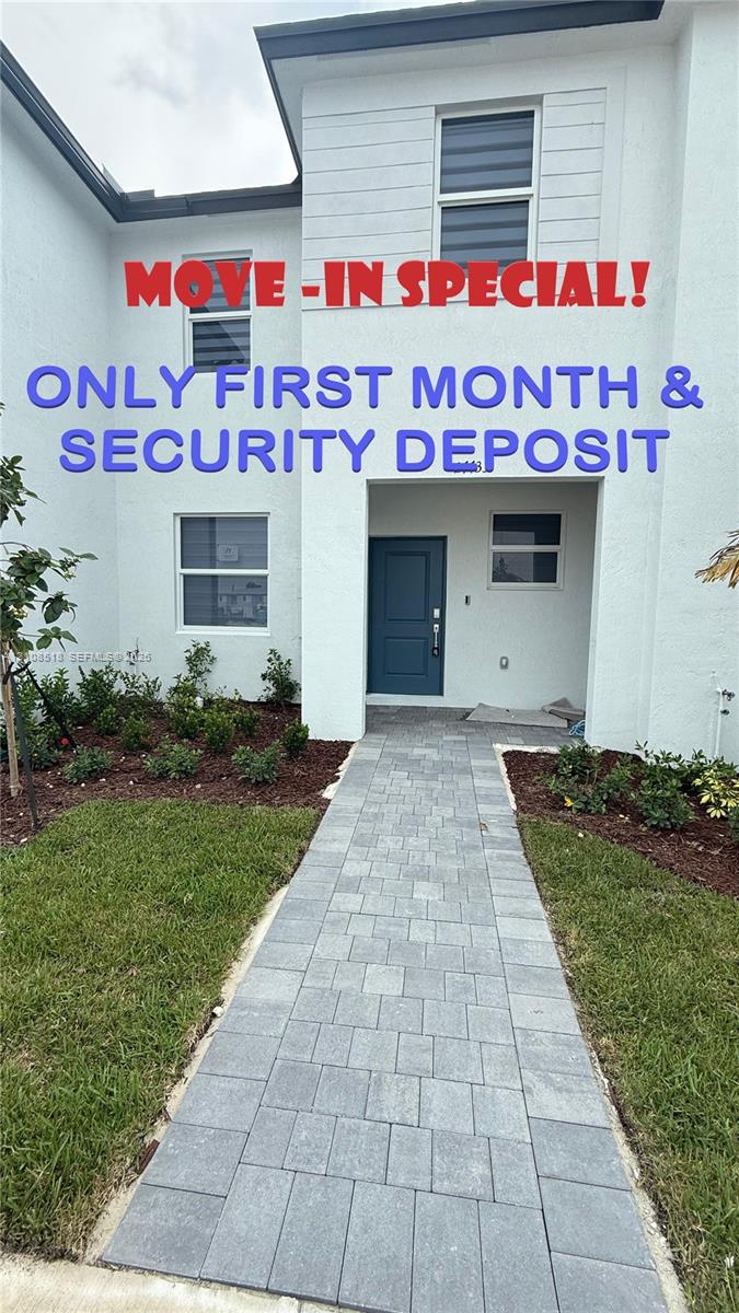 Two-story exterior featuring white stucco siding, a recessed entryway with a solid door, and a paved stone walkway