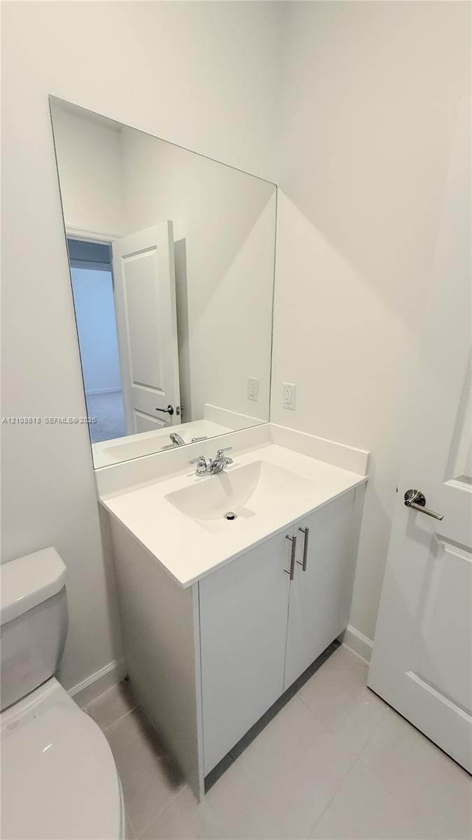 White vanity cabinet with a solid surface countertop, integrated sink, chrome dual-handle faucet, and full-length vanity mirror