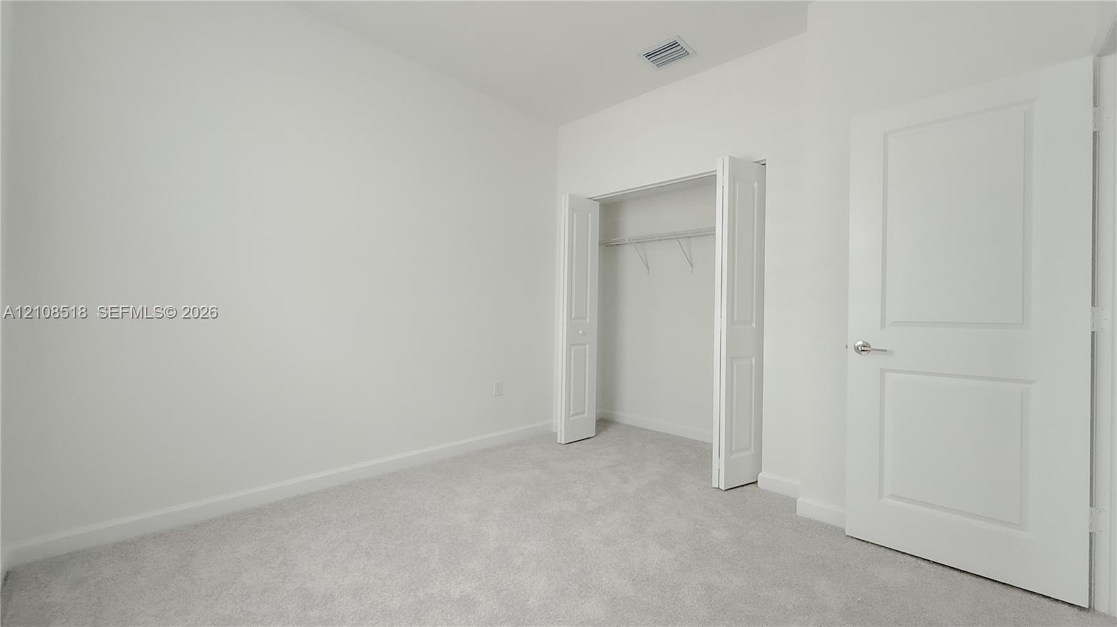 Neutral-toned carpeting, two-panel interior door, and walk-in closet with built-in shelving