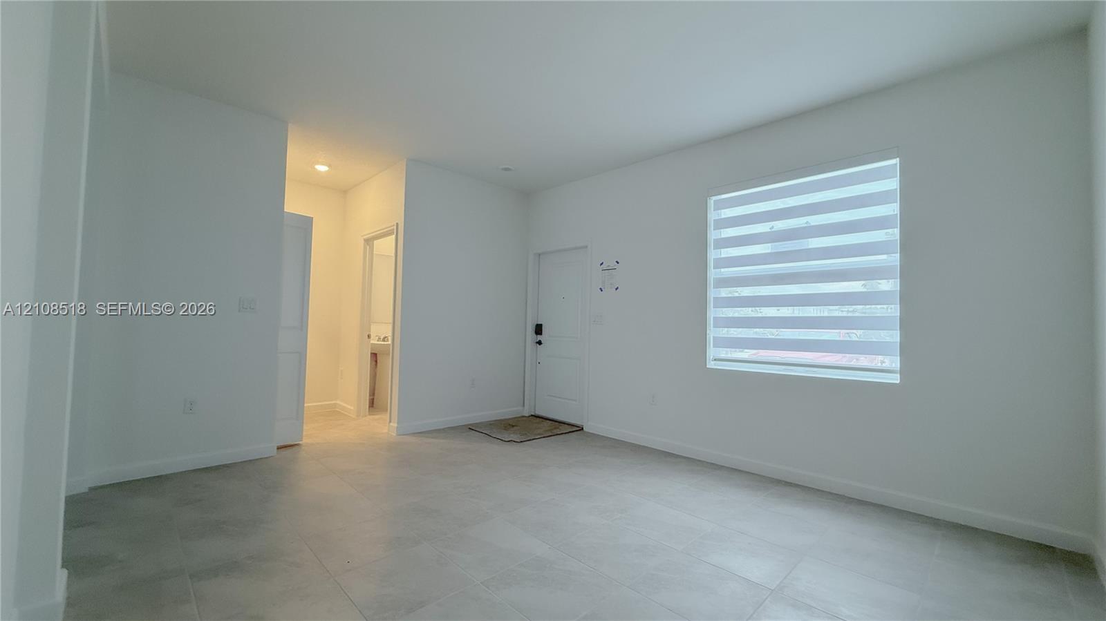 Interior space featuring neutral wall paint, large-format tile flooring, recessed ceiling lighting, and a single-panel entry door