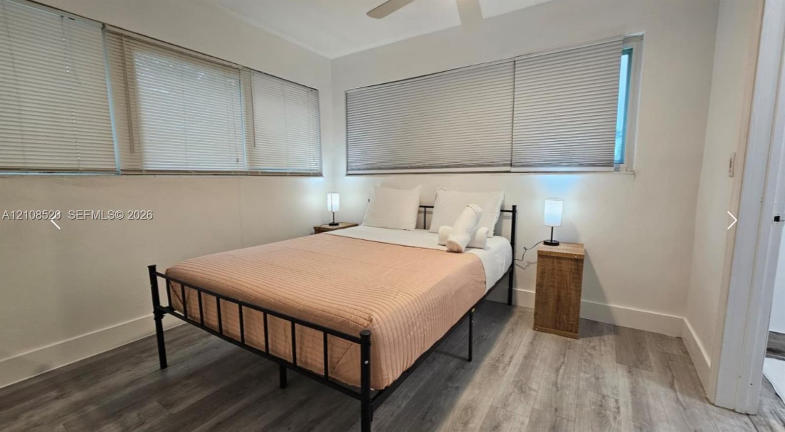 Neutral interior featuring wood-finish flooring, horizontal blinds, and a ceiling fan Neutral interior featuring wood-finish flooring, horizontal blinds, and a ceiling fan