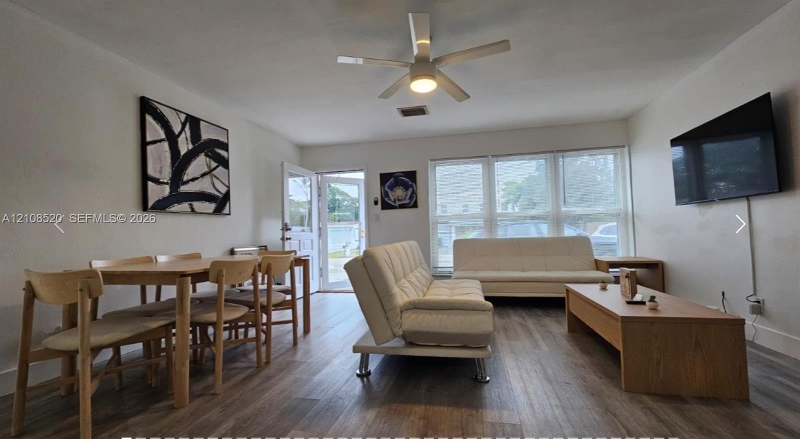 Living area featuring wood-finish flooring, a multi-pane window configuration, and a central ceiling fan Living area featuring wood-finish flooring, a multi-pane window configuration, and a central ceiling fan