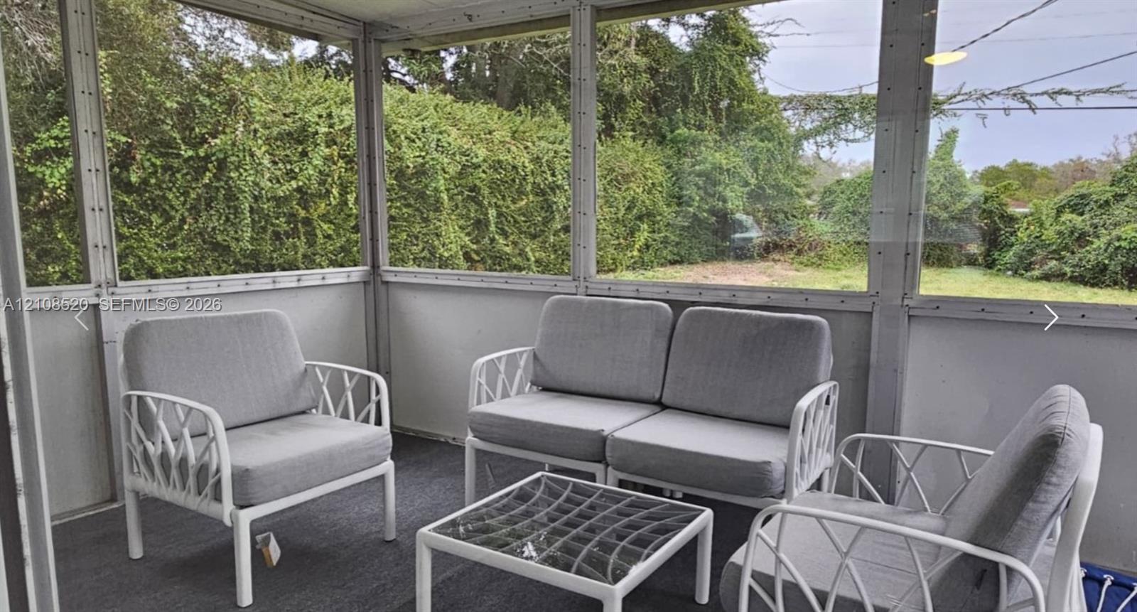 Screened-in enclosure featuring wall-to-wall mesh screening, a solid knee wall, and carpeting Screened-in enclosure featuring wall-to-wall mesh screening, a solid knee wall, and carpeting