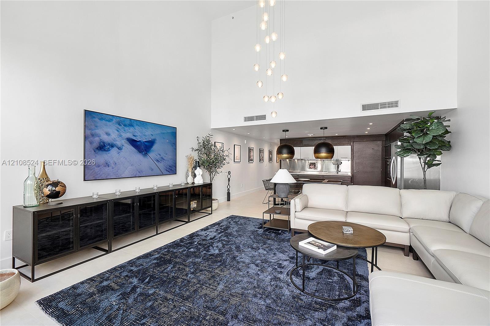 Double-height ceiling featuring a multi-globe chandelier, recessed lighting, and large-scale architectural volume